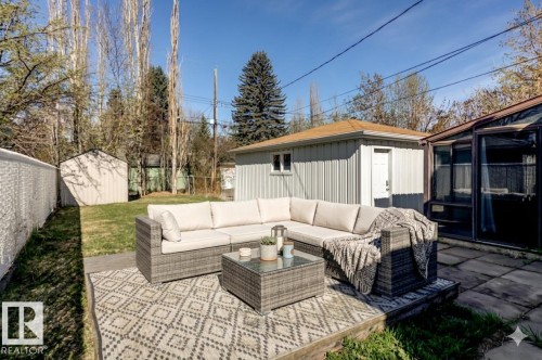 Expansive outdoor patio area featuring a paver surface, a raised platform for seating, and a sunroom with large windows - 9602 90 Street, Edmonton, AB - Outdoor