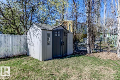 Backyard storage shed featuring a dark gray double door and two windowpanes - 9602 90 Street, Edmonton, AB - Outdoor