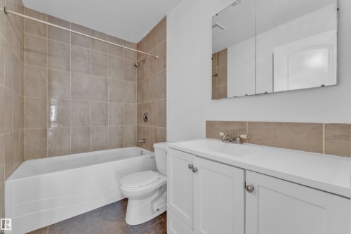 Bathroom featuring a white bathtub, ceramic tile shower surround, and a white vanity with an integrated sink - 3520 19 Avenue, Edmonton, AB - Indoor Photo Showing Bathroom
