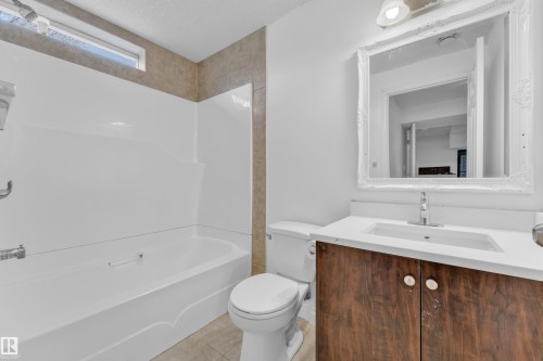 Bathroom featuring a white tub and shower surround, a rectangular window, and tile-finish walls - 3520 19 Avenue, Edmonton, AB - Indoor Photo Showing Bathroom