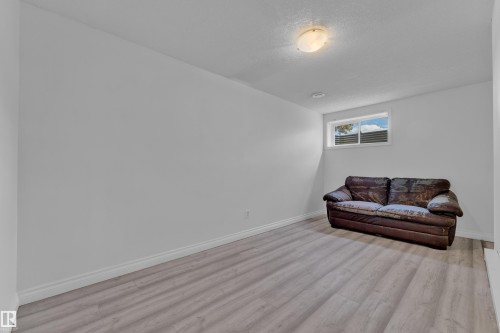 Spacious room featuring light wood-finish flooring, white baseboards, and a single window providing natural illumination - 3520 19 Avenue, Edmonton, AB - Indoor