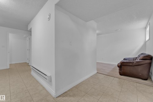 Spacious lower-level area featuring light-toned tile flooring in the foreground and wood-finish flooring in the background - 3520 19 Avenue, Edmonton, AB - Indoor Photo Showing Other Room