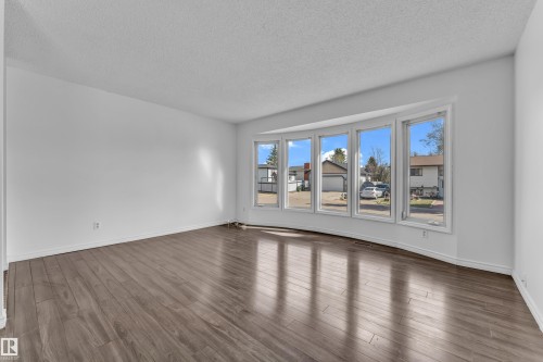 Bright interior space featuring a five-panel bay window, wood-finish flooring, and crisp white walls - 3520 19 Avenue, Edmonton, AB - Indoor Photo Showing Other Room