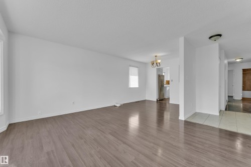 Spacious room featuring wood-finish flooring, white painted walls, and natural light from multiple windows - 3520 19 Avenue, Edmonton, AB - Indoor Photo Showing Other Room