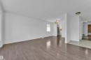 Spacious room featuring wood-finish flooring, white painted walls, and natural light from multiple windows - 3520 19 Avenue, Edmonton, AB 
