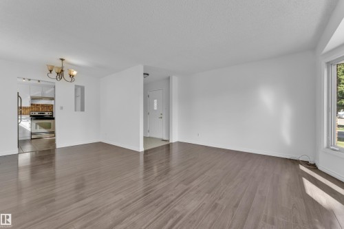 Spacious room featuring wood-finish flooring, white walls, and a large window providing natural light - 3520 19 Avenue, Edmonton, AB - Indoor Photo Showing Other Room