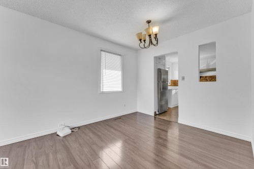 Spacious room featuring wood-finish flooring, white walls, and a multi-arm chandelier - 3520 19 Avenue, Edmonton, AB - Indoor Photo Showing Other Room