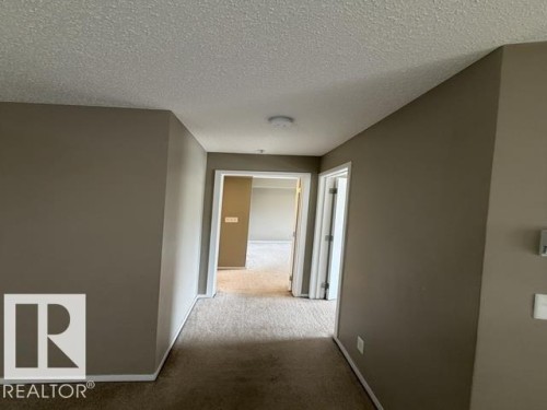 Hallway with carpet flooring, neutral tone wall paint, white trim, and overhead lighting - 321 107 Watt Common, Edmonton, AB - Indoor Photo Showing Other Room