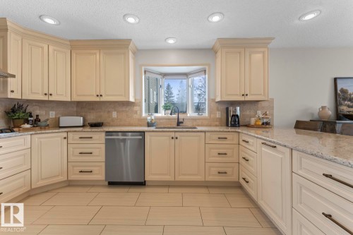 The kitchen features cream-colored cabinetry, granite countertops, a bay window, and recessed lighting - 515 Lakeshore Drive, Cold Lake, AB - Indoor Photo Showing Kitchen