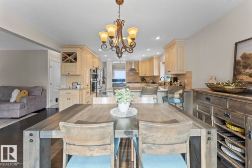 This open-concept dining area features a robust wooden table with chairs and an elegant chandelier - 515 Lakeshore Drive, Cold Lake, AB - Indoor Photo Showing Dining Room