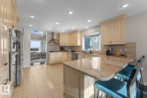The kitchen features cream-colored cabinetry, stainless steel appliances, recessed lighting, and a large central island with a granite countertop - 515 Lakeshore Drive, Cold Lake, AB - Indoor Photo Showing Kitchen With Upgraded Kitchen