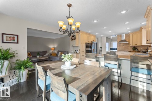 This property features dark hardwood flooring throughout, recessed lighting in the kitchen area, and a kitchen with light-toned cabinetry and a stainless steel range hood - 515 Lakeshore Drive, Cold Lake, AB - Indoor Photo Showing Dining Room
