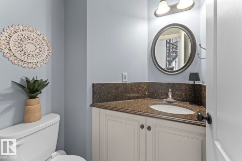 The bathroom features a vanity with a granite countertop and a white sink, a mirror with a dark frame, and a white toilet - 515 Lakeshore Drive, Cold Lake, AB - Indoor Photo Showing Bathroom
