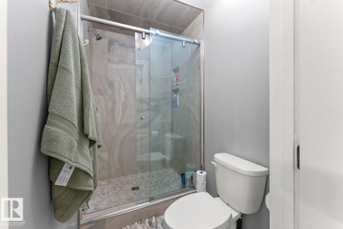 The bathroom features a shower with sliding glass doors and tiled walls, and a white toilet - 515 Lakeshore Drive, Cold Lake, AB - Indoor Photo Showing Bathroom