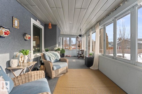 This bright sunroom features extensive windows, a textured gray wall, and a slatted ceiling, offering an inviting space - 515 Lakeshore Drive, Cold Lake, AB - Outdoor With Deck Patio Veranda With Exterior