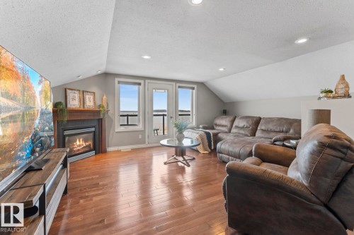 The living area features warm hardwood floors, a fireplace with a wooden mantle, and recessed lighting - 515 Lakeshore Drive, Cold Lake, AB - Indoor Photo Showing Living Room With Fireplace