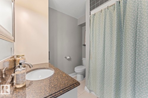 Bathroom featuring a vanity with a dark speckled countertop and an oval sink, alongside a toilet and a shower area with a curtain - 515 Lakeshore Drive, Cold Lake, AB - Indoor Photo Showing Bathroom