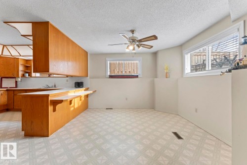 This open-concept area features a kitchen with wood cabinetry and a counter-height bar - 515 Lakeshore Drive, Cold Lake, AB - Indoor Photo Showing Kitchen