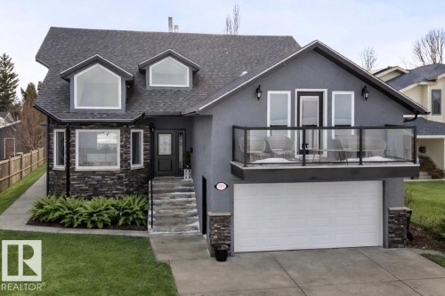 The property features a dark gray exterior, a prominent balcony with a glass railing, and a spacious two-car garage - 515 Lakeshore Drive, Cold Lake, AB - Outdoor With Facade