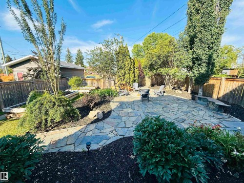 The property features a spacious backyard with a flagstone patio, mature trees, and landscaped garden beds - 515 Lakeshore Drive, Cold Lake, AB - Outdoor
