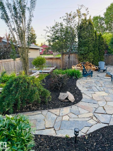 The property features a flagstone patio, well-maintained garden beds with dark mulch, and various mature plantings - 515 Lakeshore Drive, Cold Lake, AB - Outdoor