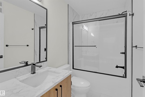 Bathroom featuring a modern vanity with a white marble-look countertop, integrated sink, and matte black faucet - 7936 91 Avenue, Edmonton, AB - Indoor Photo Showing Bathroom