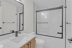 Bathroom featuring a modern vanity with a white marble-look countertop, integrated sink, and matte black faucet - 