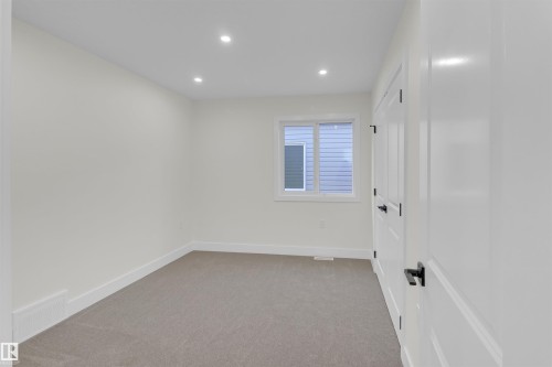 Neutral-toned carpeting complements light wall finishes in this room featuring recessed lighting and a window with white trim - 7936 91 Avenue, Edmonton, AB - Indoor Photo Showing Other Room