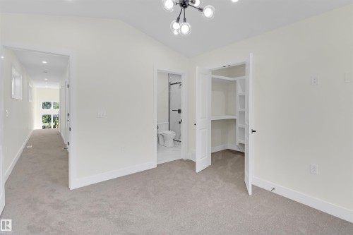 Carpeted room featuring a vaulted ceiling and a contemporary chandelier - 7936 91 Avenue, Edmonton, AB - Indoor Photo Showing Other Room