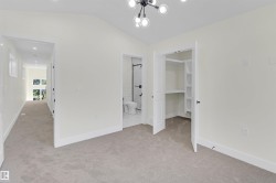 Carpeted room featuring a vaulted ceiling and a contemporary chandelier - 