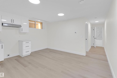 Open living area featuring light wood-finish flooring, recessed lighting, and white walls - 7936 91 Avenue, Edmonton, AB - Indoor Photo Showing Other Room