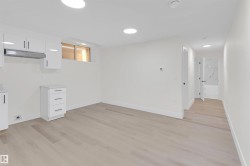 Open living area featuring light wood-finish flooring, recessed lighting, and white walls - 