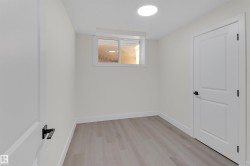 Interior room featuring light wood-finish flooring, white walls, and a white ceiling with a circular flush-mount light fixture - 
