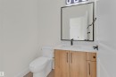Bathroom featuring a wood-finish vanity with a rectangular sink, a light-toned countertop, and matte black fixtures - 7936 91 Avenue, Edmonton, AB  - Indoor Photo Showing Bathroom 