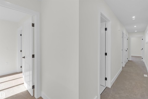 Hallway with neutral carpeting, white walls, and multiple white paneled doors with matte black hardware - 7936 91 Avenue, Edmonton, AB - Indoor Photo Showing Other Room