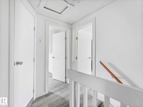Hallway featuring light wood-finish flooring, white walls, and multiple panel doors with polished chrome hardware - 4322 53 Street, Wetaskiwin, AB - Indoor Photo Showing Other Room