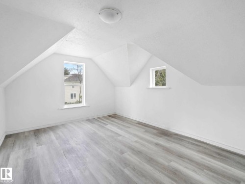 Attic room featuring a vaulted ceiling, wood-finish flooring, recessed window, and flush mount lighting - 4322 53 Street, Wetaskiwin, AB - Indoor Photo Showing Other Room