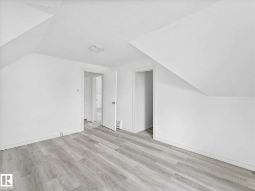 Attic space featuring light wood-finish flooring, white painted walls, and a sloped ceiling - 4322 53 Street, Wetaskiwin, AB - Indoor Photo Showing Other Room