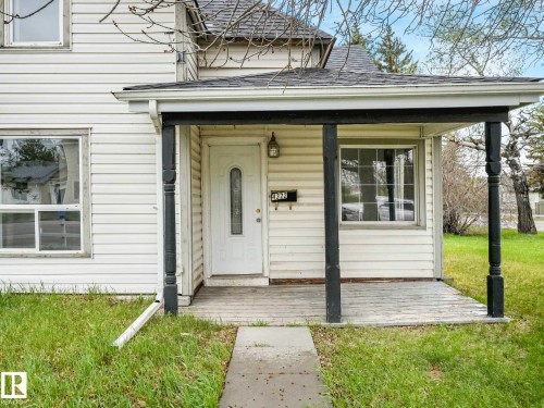 Front porch entrance with a white paneled door, two front-facing windows, dark support columns, and light siding - 4322 53 Street, Wetaskiwin, AB - Outdoor