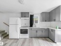 Contemporary kitchen featuring light gray shaker-style cabinetry with dark hardware, white countertops, and a stainless steel sink with a gooseneck faucet - 4322 53 Street, Wetaskiwin, AB  - Indoor Photo Showing Kitchen 