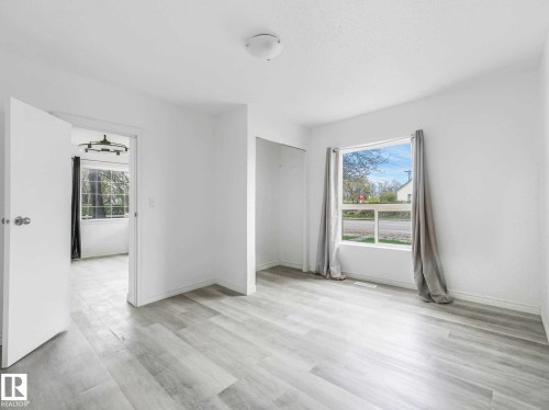 Room featuring light-toned wood-finish flooring, white walls, and a window with a street view - 4322 53 Street, Wetaskiwin, AB - Indoor Photo Showing Other Room