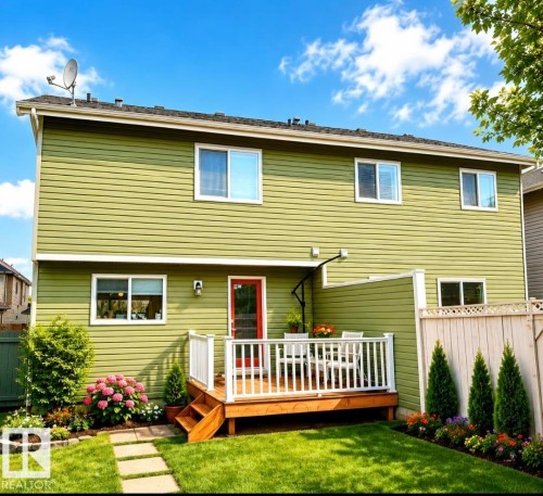Private backyard featuring a ground-level wood deck with white railings, a red exterior door, and a stone paver path - 225 51A Street, Edmonton, AB 