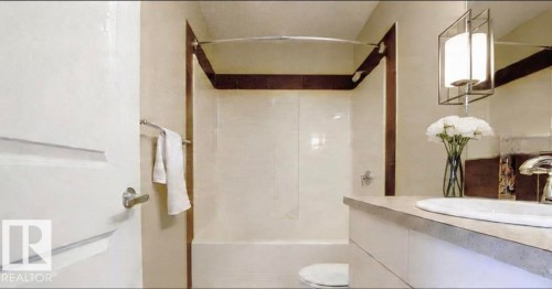 Bathroom featuring a white vanity with an integrated sink, polished chrome faucet, and a contemporary pendant light fixture - 225 51A Street, Edmonton, AB 