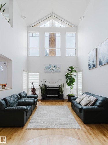 Great room featuring vaulted ceilings, a fireplace with a white mantel, and wood-finish flooring - 342 O'Connor Close, Edmonton, AB - Indoor Photo Showing Living Room