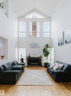 Great room featuring vaulted ceilings, a fireplace with a white mantel, and wood-finish flooring - 