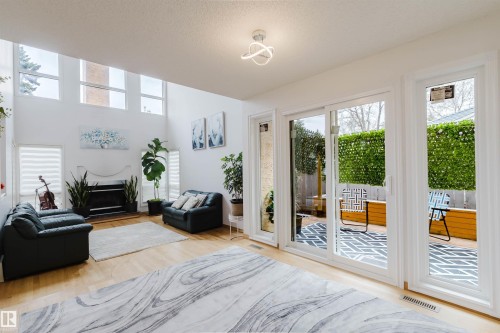 Spacious living area featuring high ceilings, hardwood flooring, a fireplace with a white mantel, and large windows providing ample natural light - 342 O'Connor Close, Edmonton, AB - Indoor