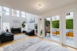 Spacious living area featuring high ceilings, hardwood flooring, a fireplace with a white mantel, and large windows providing ample natural light - 