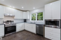 Kitchen featuring white cabinetry, stainless steel appliances, grey countertops, a white subway tile backsplash, and recessed lighting - 