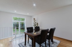 Bright dining area featuring light wood-finish flooring, recessed lighting, and a white railing overlooking a lower level - 