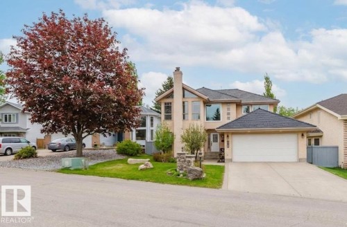 Stucco exterior with a two-car garage, pitched shingle roof, mature front yard tree, and a concrete driveway - 342 O'Connor Close, Edmonton, AB - Outdoor With Facade